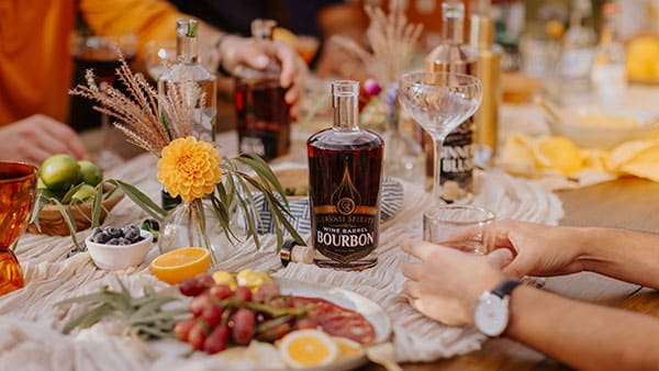 Gervasi Spirits Wine Barrel Bourbon on a rustic table with fresh fruit, charcuterie, and fall florals during an outdoor celebration