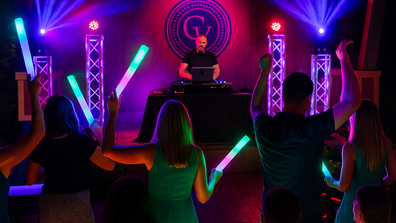 DJ-led summer dance party at The Piazza at Gervasi Vineyard, with guests waving glow sticks and vibrant lighting creating a festive atmosphere.