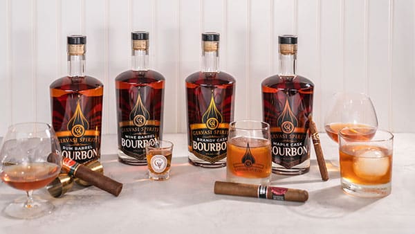 Assortment of Gervasi Spirits bourbon bottles with cigars and whiskey glasses arranged for a premium Father’s Day tasting experience.