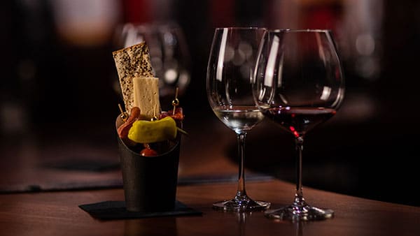 A small charcuterie cone and wine glasses set up for tasting at The Cave at Gervasi Vineyard.