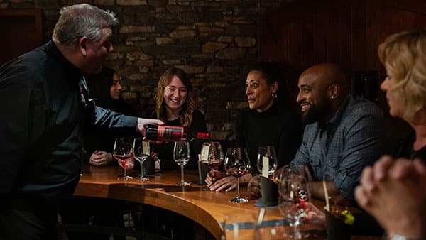 Sommelier pouring wine during an intimate wine tasting experience at The Cave at Gervasi Vineyard.