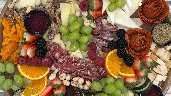 Gourmet charcuterie board with cured meats, cheeses, fruits, nuts, and spreads arranged for cheese and wine pairing