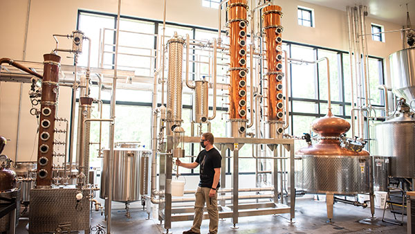 A distiller works among towering copper stills inside The Still House at Gervasi Vineyard in Canton, Ohio, where premium Gervasi Spirits are crafted on-site.