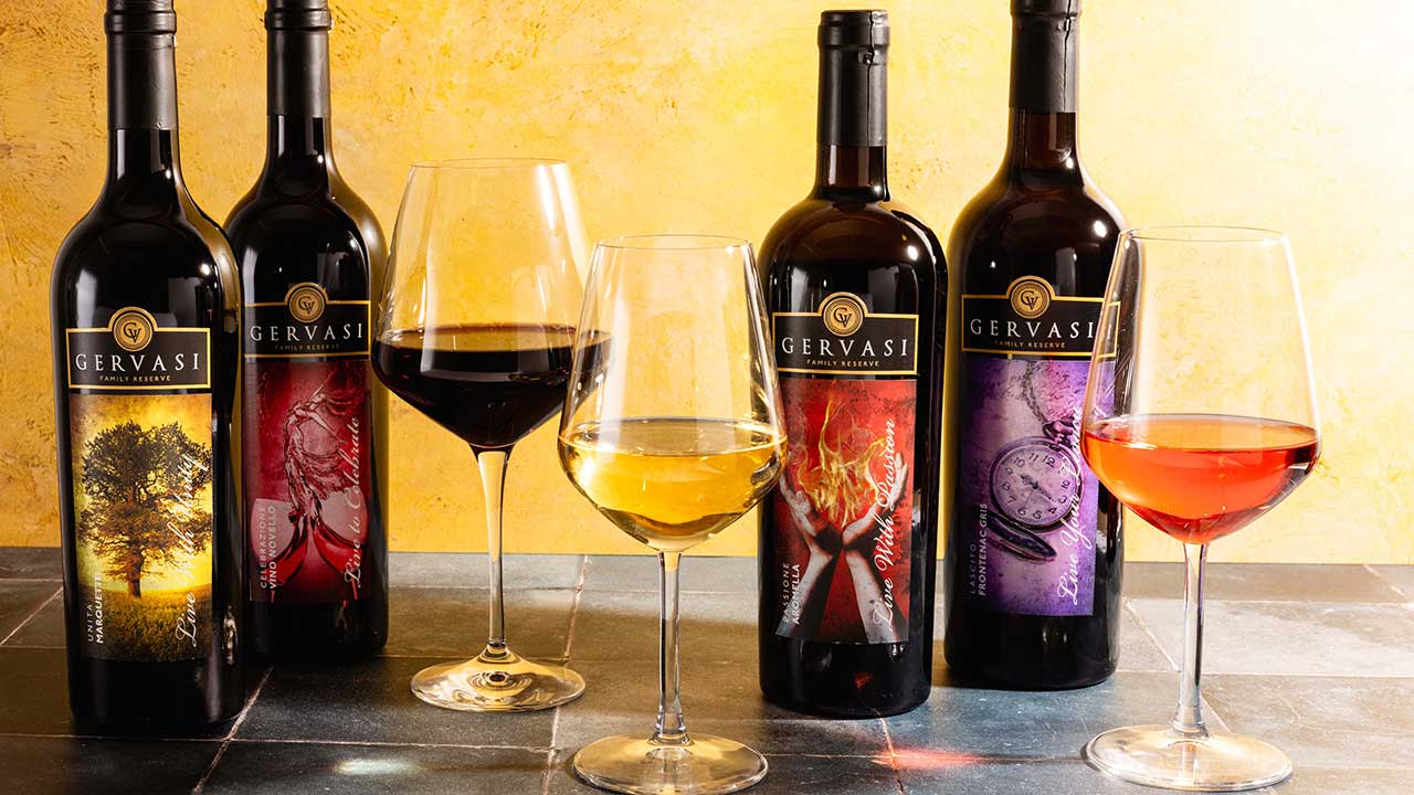 Lineup of Gervasi Vineyard’s award-winning Family Reserve wines with glasses of red, white, and rosé, set against a warm backdrop.