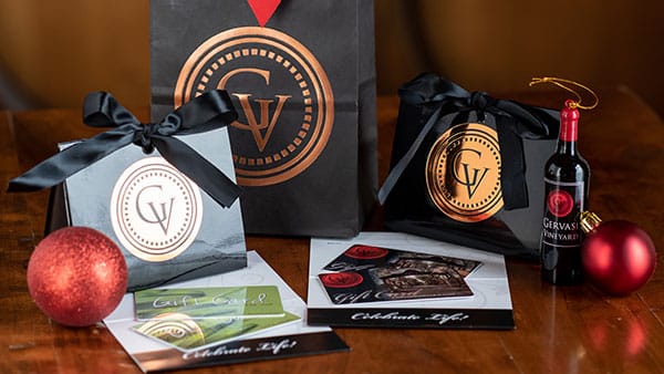 Gervasi Vineyard and The Spa gift cards elegantly packaged with holiday-themed wrapping, ornaments, and branded mini wine bottle.