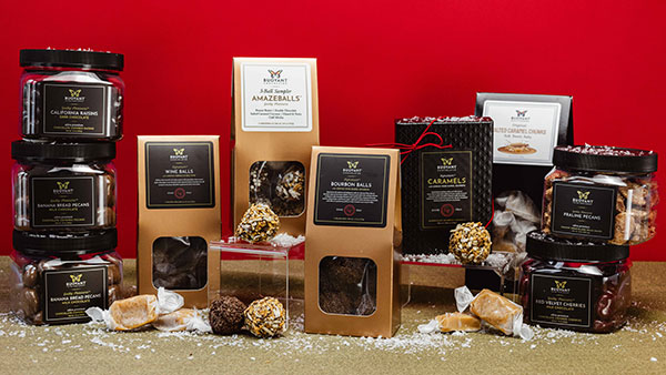 An assortment of gourmet holiday sweets from The Marketplace at Gervasi Vineyard including bourbon balls, wine balls, caramels, and chocolate-covered cherries with gift-ready packaging.