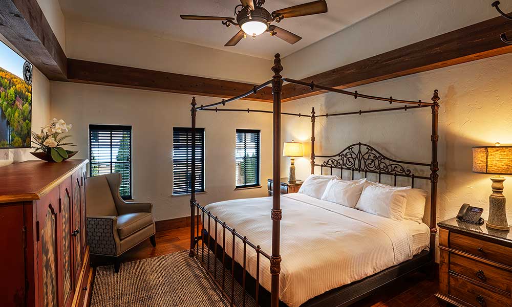 Elegant two-level Villa Suite at Gervasi Vineyard with wrought-iron canopy bed, cozy lighting, and scenic views through multiple windows