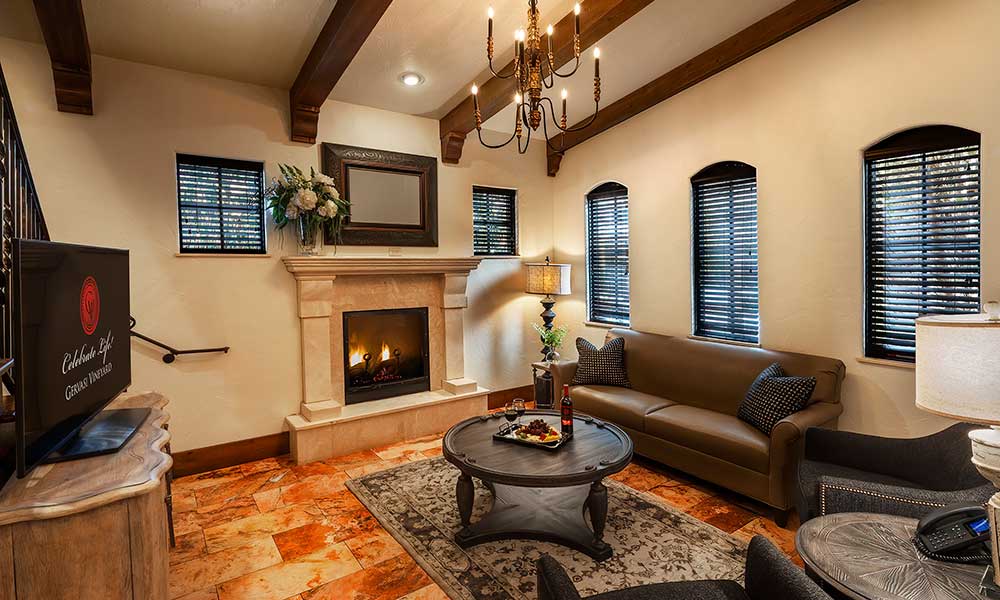 Villa Suite living area at Gervasi Vineyard with stone fireplace, comfortable seating, chandelier, and rich Tuscan-inspired décor
