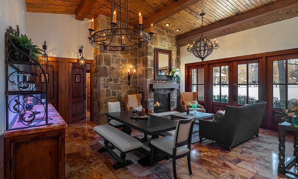 Gervasi Vineyard Villa common area featuring a stone fireplace, rustic chandeliers, and inviting dining and lounge seating