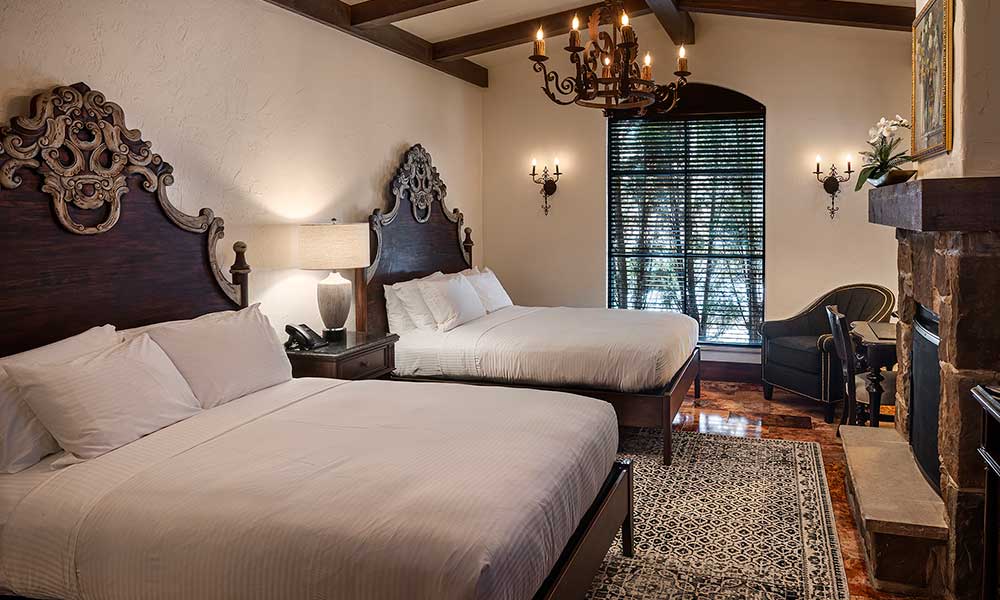 Villa double queen bedroom at Gervasi Vineyard with ornate headboards, in-room fireplace, and classic European touches