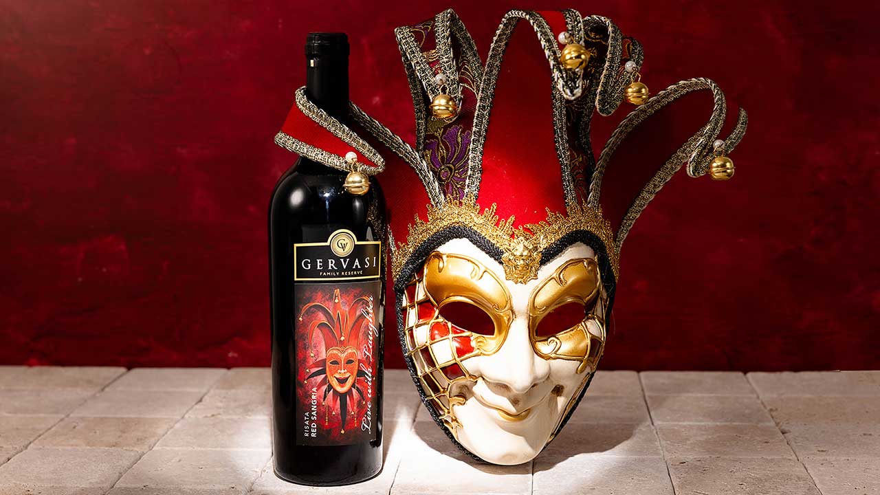 Gervasi Vineyard’s Risata Red Sangria bottle posed next to a dramatic Venetian-style carnival mask, emphasizing the wine’s playful spirit and bold personality.