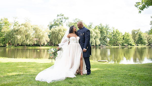Bride and groom standing lakeside in an elegant wedding portrait at Gervasi Vineyard.