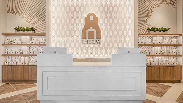 Modern and elegant lobby at The Spa at Gervasi Vineyard, featuring sleek white counters, signature branding, and retail shelves with spa products.