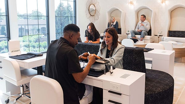 Nail technician providing a manicure to a smiling guest at The Spa at Gervasi Vineyard, where guests enjoy upscale nail care and a relaxing atmosphere.