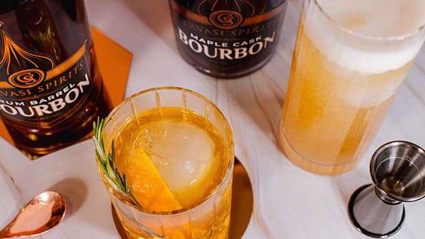 Craft bourbon cocktails made with Gervasi Spirits Maple Cask and Rum Barrel Bourbons, served with citrus garnish on marble bar