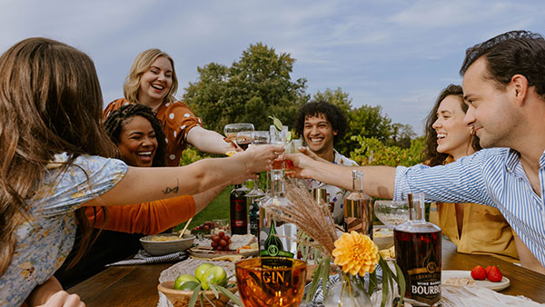 Group of friends toasting with Gervasi Spirits gin and bourbon at an outdoor vineyard gathering