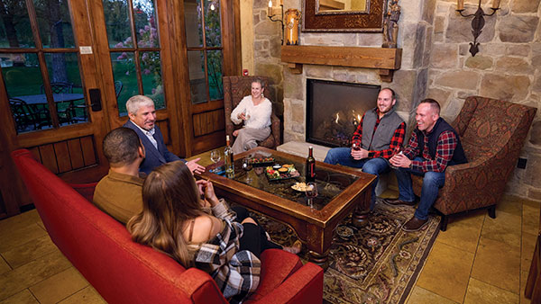 Group of friends sharing drinks and conversation by the fireplace in a Gervasi Vineyard Villa.