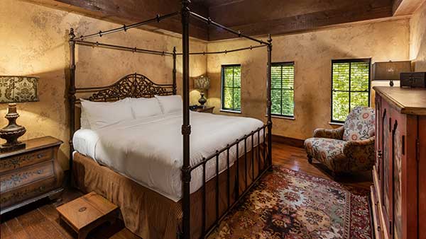 Interior of a Gervasi Vineyard Villa suite featuring a wrought iron canopy bed, rich textures, and warm, rustic finishes.