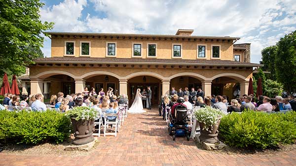Wedding ceremony taking place in front of the Villa Grande at Gervasi Vineyard, with rows of seated guests and Italian-style architecture as a backdrop