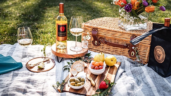 Elegant wine picnic featuring Gervasi white wine, charcuterie, and fresh flowers on the estate grounds.