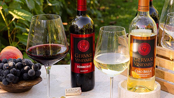 Gervasi Vineyard Nebbiolo and Ciao Bella Chardonnay wines with full glasses and fruit platter on a vineyard tasting table